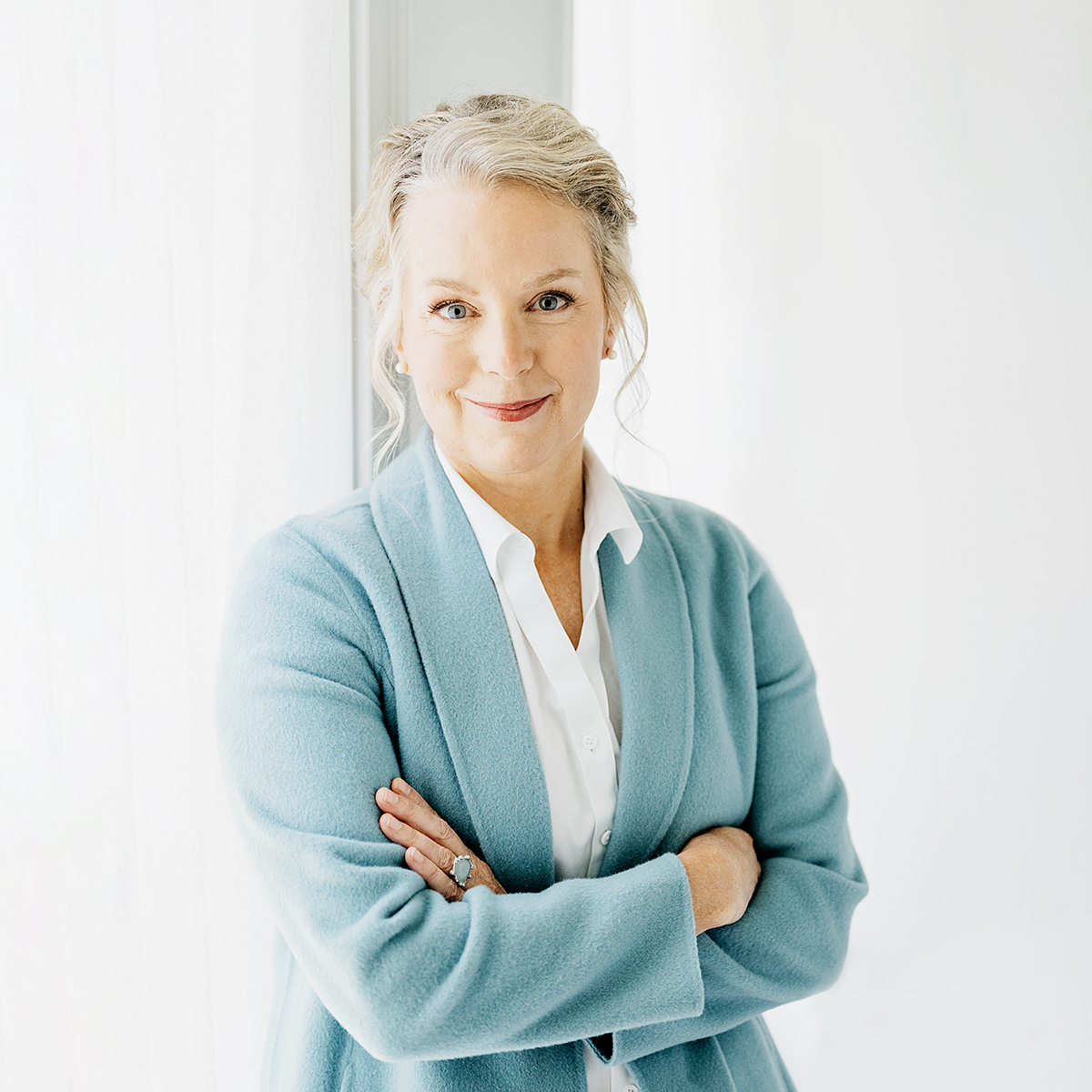 Michelle Roy, PA-C, in a light blue jacket over a white shirt, smiling with arms crossed
